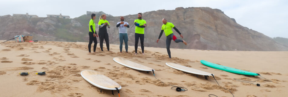 Group surf lesson warm-up on beach with surfboards and coastal cliffs backdrop