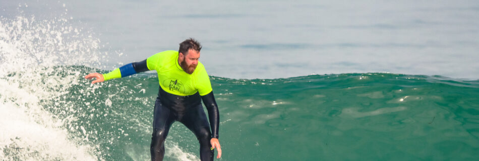 Male surfer trimming along wave face in safety gear