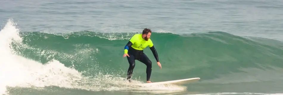 Male surfer riding green wave in safety yellow rashguard