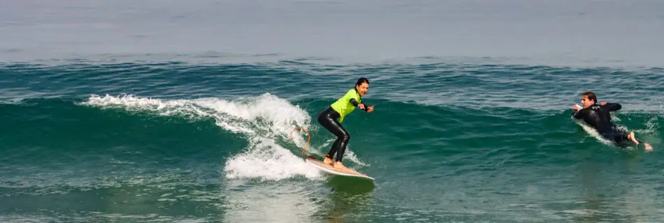 Female surfer riding wave with style in safety yellow gear