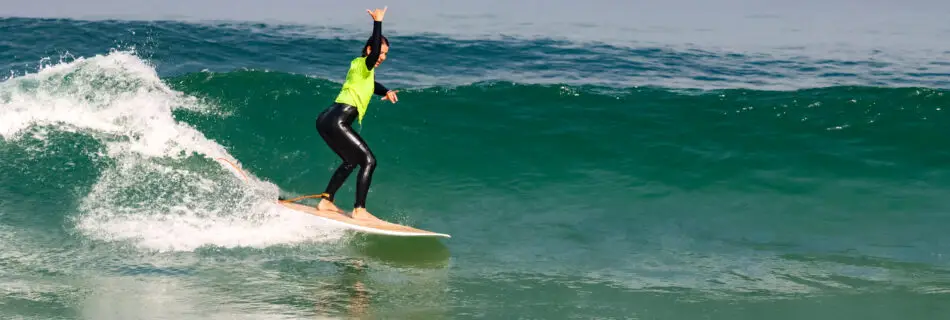 Female surfer celebrating with arms raised while riding wave