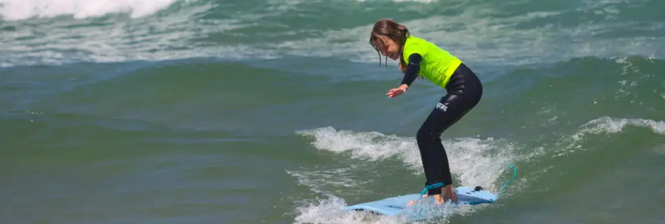 Our youngest surfer wading in shallow water with their surfboard