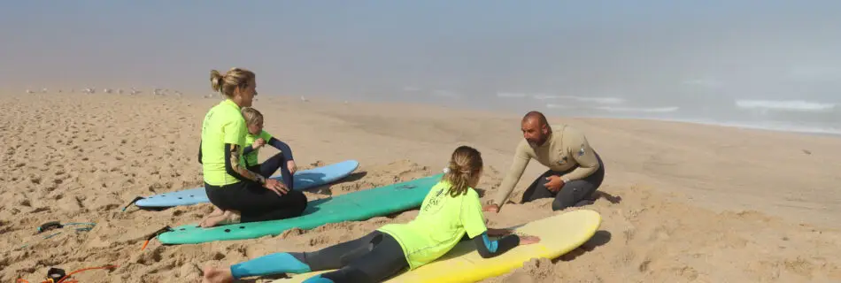 Surf instructor teaching pop-up technique to students on surfboards on sandy beach