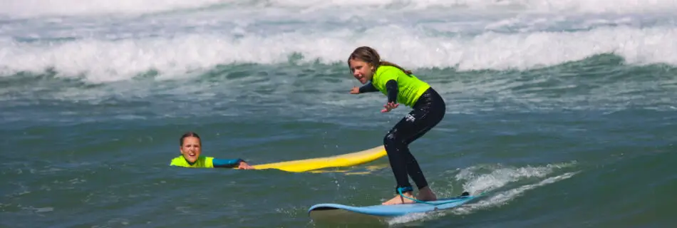 Student standing up on surfboard riding white water