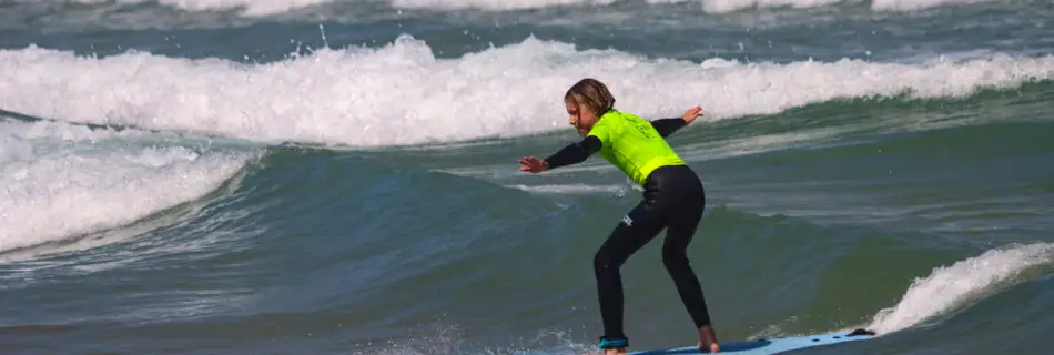 Youngest family member riding wave on yellow softboard with encouraging family nearby