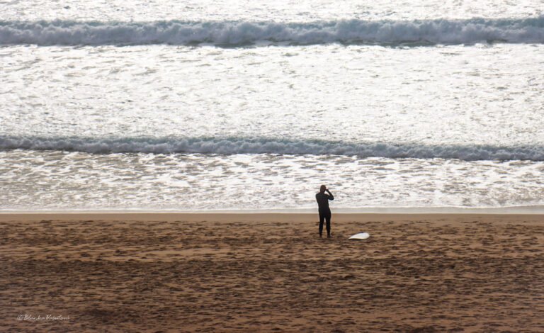 Surfing in Portugal by Month: Water Temperature, Waves and the Best Time to Go 2 Lone surfer standing on the beach watching the waves before going in